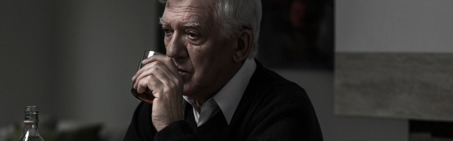 An Elderly man drinking an alcohol alone